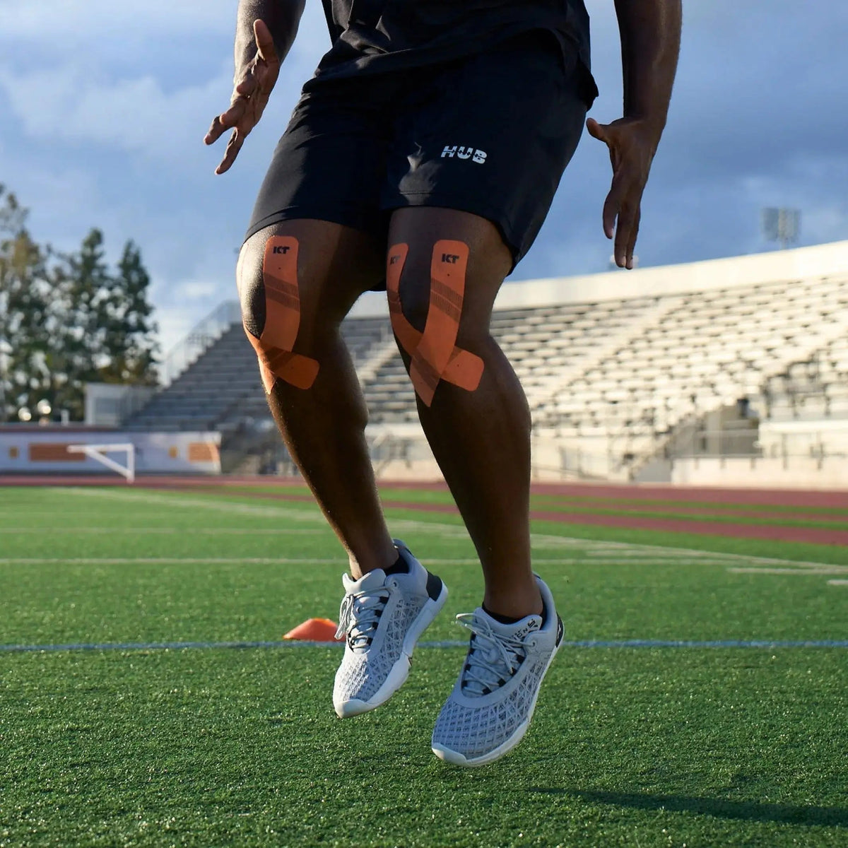 Man wearing KT Tape Pro on Kknees on field in stadium exercising#color_jet-black
